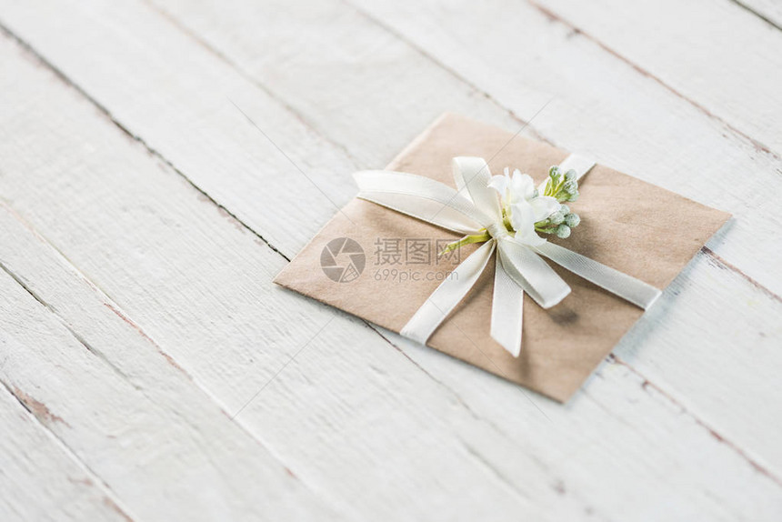 白色木制桌面上装有花和丝带邀请卡婚图片