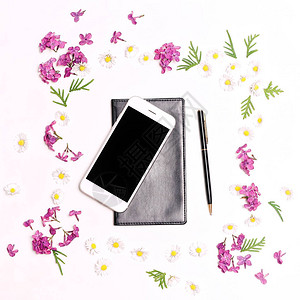 白色桌子背景上的手机笔记本笔花和硅花的模型平面图片