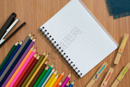 空白笔记本彩色笔记本和木制桌上的订书机图片