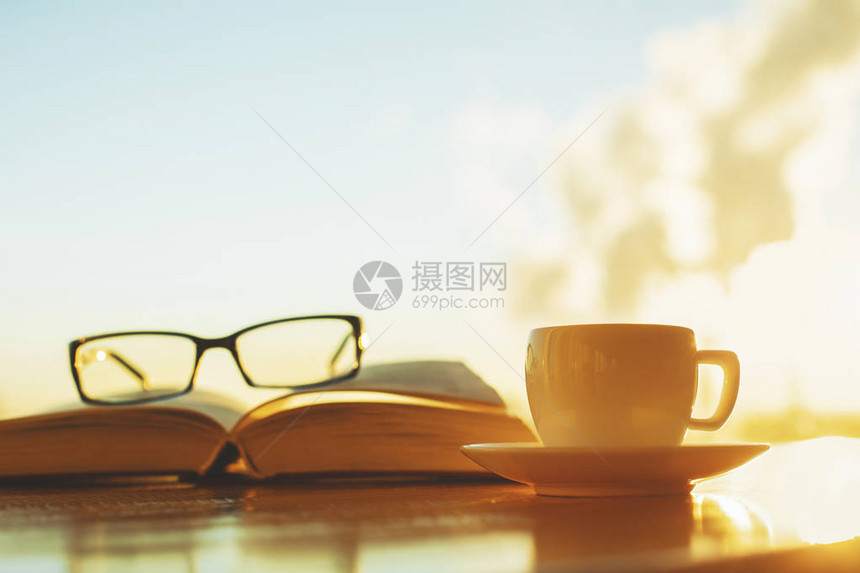 在模糊的天空背景上贴近书籍眼镜和咖啡杯闲图片