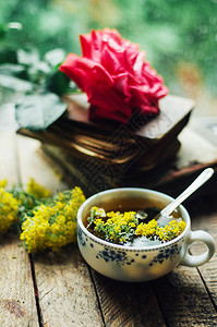 浪漫的背景与一杯茶鲜花和打开的书在木桌咖啡杯书和桌上图片