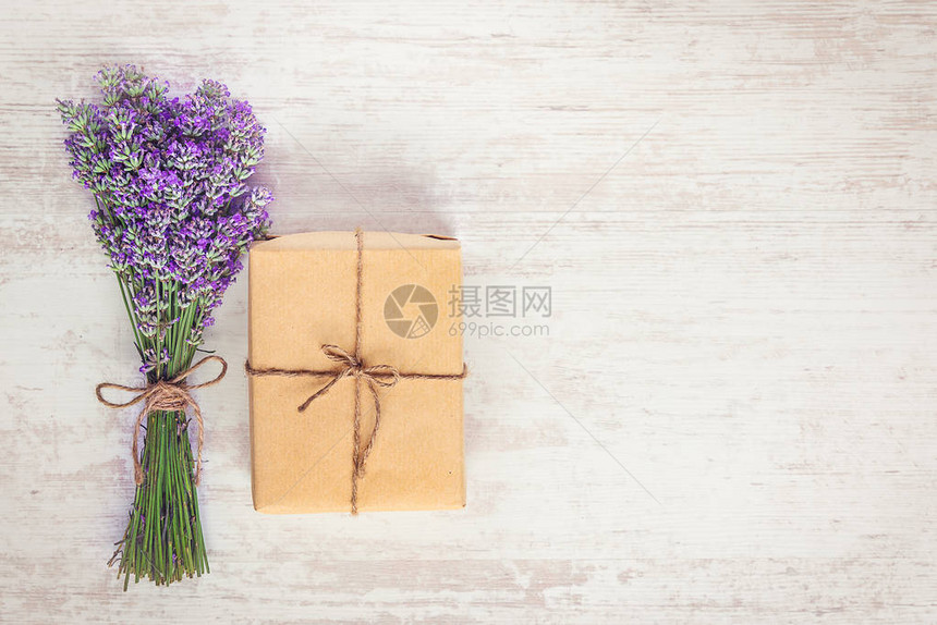 白色木质生锈背景上包裹在克拉夫纸和熏衣草花束上的礼品盒的顶端视图图片