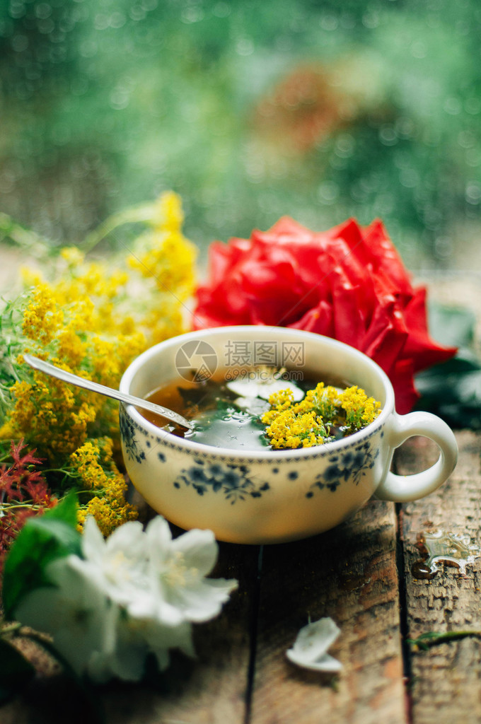 浪漫的背景与一杯茶鲜花和打开的书在木桌咖啡杯书和桌上图片