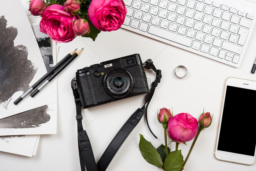 现代智能手机计算机键盘粉红花和白色桌上的照相机自由职业图片