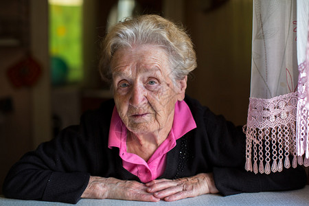 坐在房子桌前的年长妇女的肖像图片