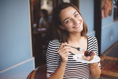 吃草莓芝士蛋糕的年轻女人图片