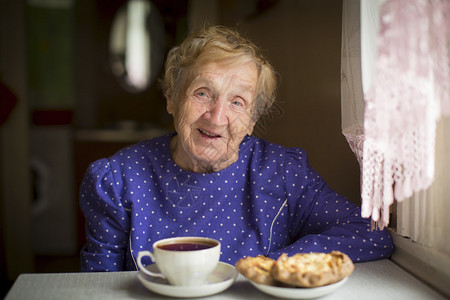 快乐的老女人喝茶坐在房图片