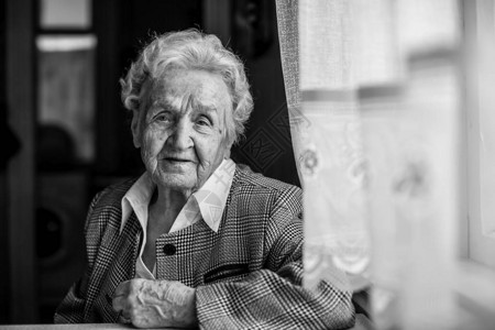 老年妇女坐在桌旁的黑白肖像图片