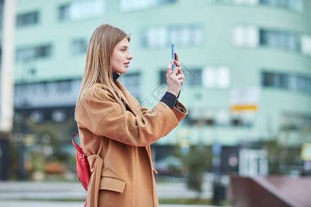 一个年轻女孩在市中心拍照用手机拍照的女孩莫斯科图片