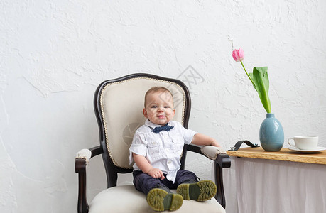 时装小男孩坐在白色房间的扶手椅图片