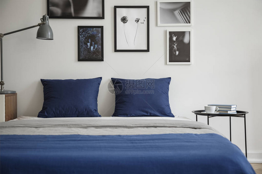 白卧室内面桌和灯之间床铺的海军蓝色枕图片