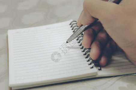 用笔在记本上写字的人手合上图片
