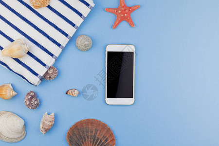 沙滩巾贝壳海星和智能手机的顶视图在柔和的蓝色背景上图片