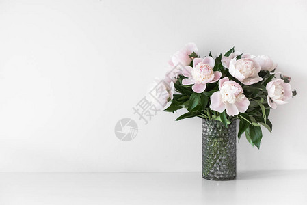 在白色墙壁附近的花瓶中用鲜花装饰背景图片