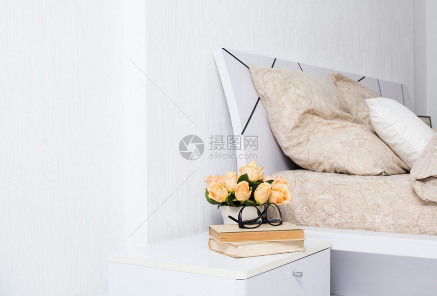 里面有明亮的白色卧室舒适的床和米色麻布床边桌子上图片