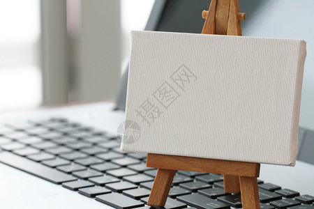 笔记本电脑上的空白画布和木制画架作为概念图片
