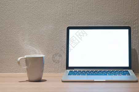 带光白空屏幕的手提电脑木制桌上的白色咖啡杯和图片