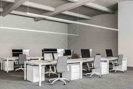 公司办公室内部配有灰色地毯和一排白色电脑桌图片