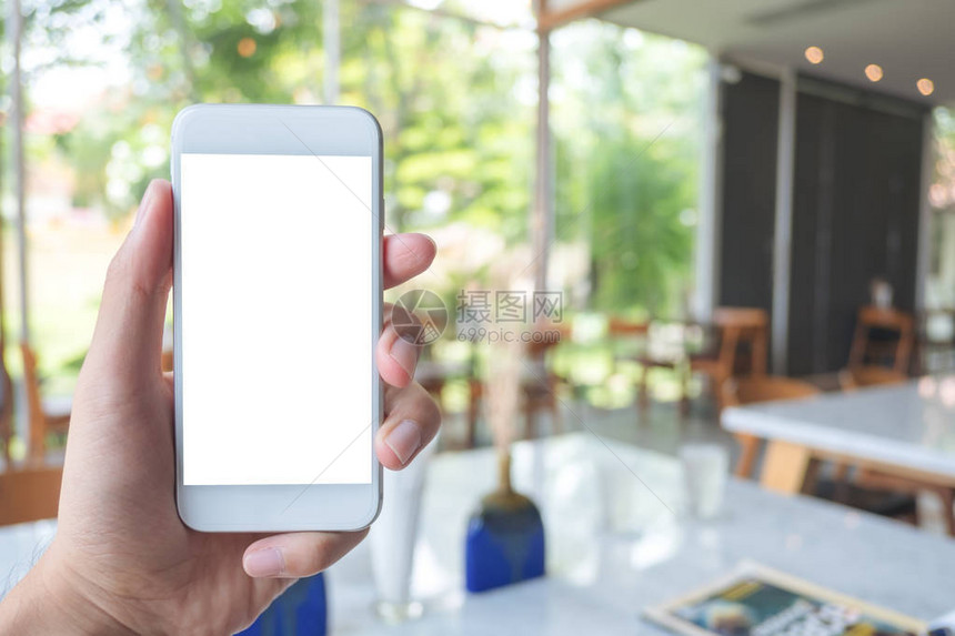 现代咖啡馆内手持白色手机带空白屏图片