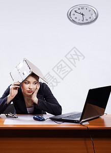 坐在工作场所的美丽无聊商业妇女的办公室肖像图片