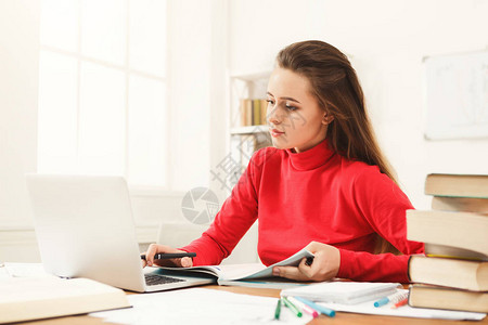 在工作台学习的年轻女孩集中的女学生读书和在笔记本电脑上工作教图片