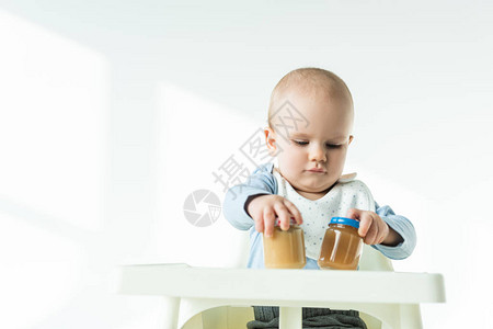 可爱的婴儿在白色背景的喂养椅桌上图片