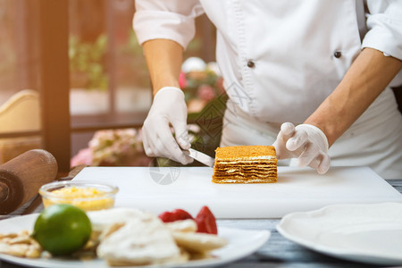 男手触摸蛋糕白色烹饪板上的蛋糕厨师准备的蜂蜜蛋糕餐厅图片