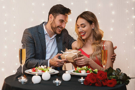 情人节庆祝爱人以浪漫的礼物在餐厅吃晚饭时给女朋友一个惊背景图片