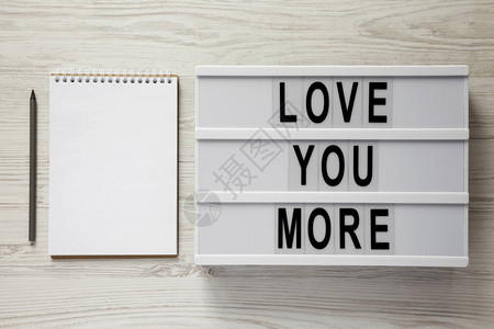 写着爱你更多的文字空白笔记本和铅笔的灯盒图片