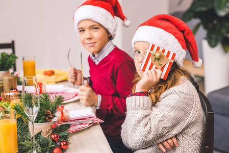 可爱的快乐的弟和妹坐在圣诞节桌边女孩图片