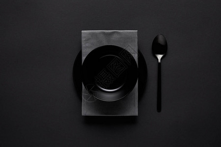 黑碗勺子厨房毛巾和黑桌上的盘子图片