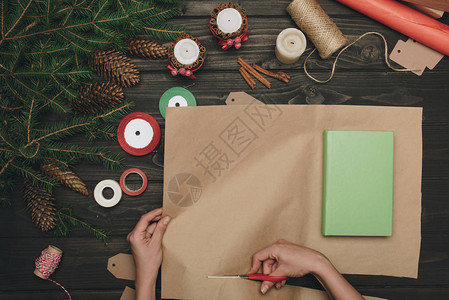 以木制桌上的纸包着圣诞节礼物的妇图片