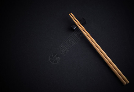 黑棉织物背景上的两支竹筷背景图片
