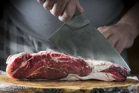屠夫用切肉刀在板上切一块肉背景图片