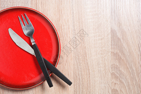 厨房桌子上的红盘子叉子和刀子顶视图图片