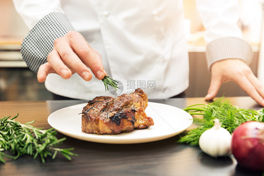 厨师用香草装饰烤肉图片