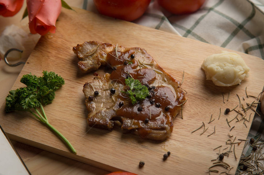 烤猪肉烧烤牛排和餐桌上砧板上的配菜图片