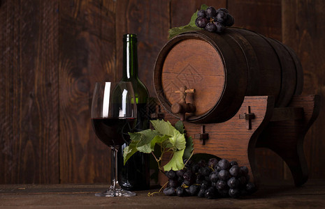 瓶红葡萄酒葡萄和木桶图片