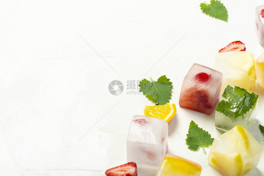 白色石头背景上带有水果和薄荷叶的冰块水果冰概念图片