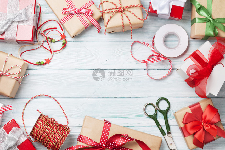 白木桌顶视图上的圣诞礼物盒和礼品包装材料图片