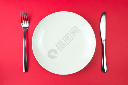 安排一个白餐盘用叉子和刀具在红图片