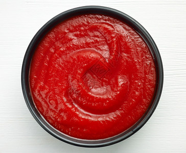 白色木桌上的一碗番茄酱或番茄酱图片