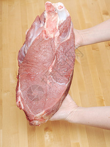 一块肉在女手中在木背景图片
