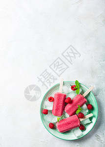 绿色盘子上印有冰草莓和薄荷的自制蓝莓冰棒图片