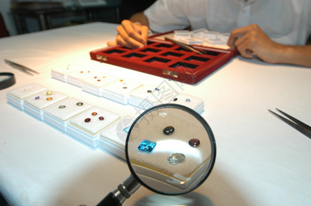 多色晶体在靠近男人的桌子上的放大镜下图片