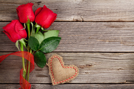 红玫瑰和情人节的心放在木制背景上顶视图片