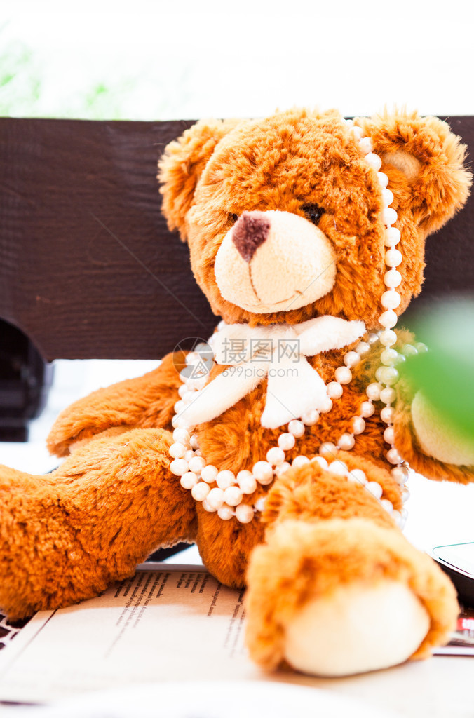 带珍珠的毛绒玩具熊坐在桌子上图片
