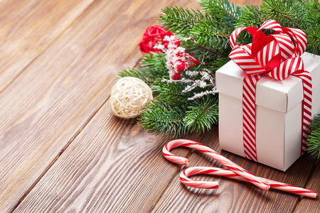圣诞礼品盒糖果甘蔗和木制桌上的fir树枝用图片