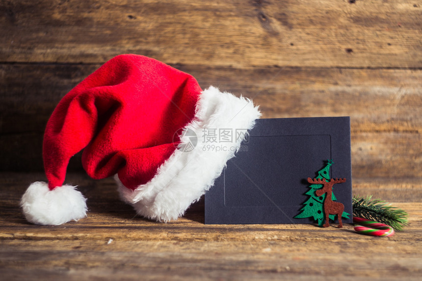 圣诞贺卡和礼物与圣诞老人帽子在木制背景与糖果手杖冷杉树枝图片