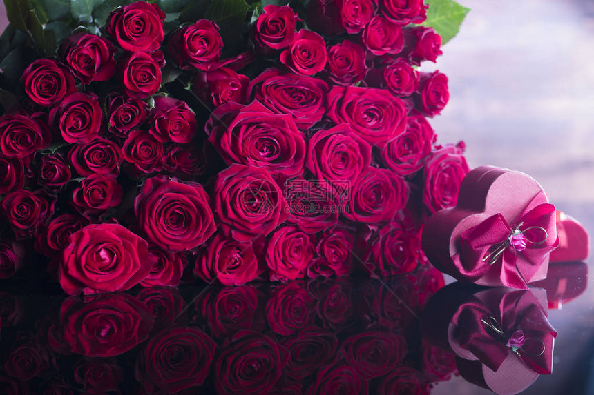 玻璃桌上的玫瑰花束和心形盒子图片